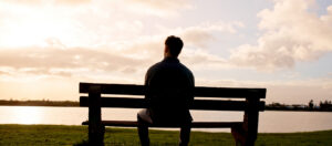 Man sat on a bench overlooking a lake